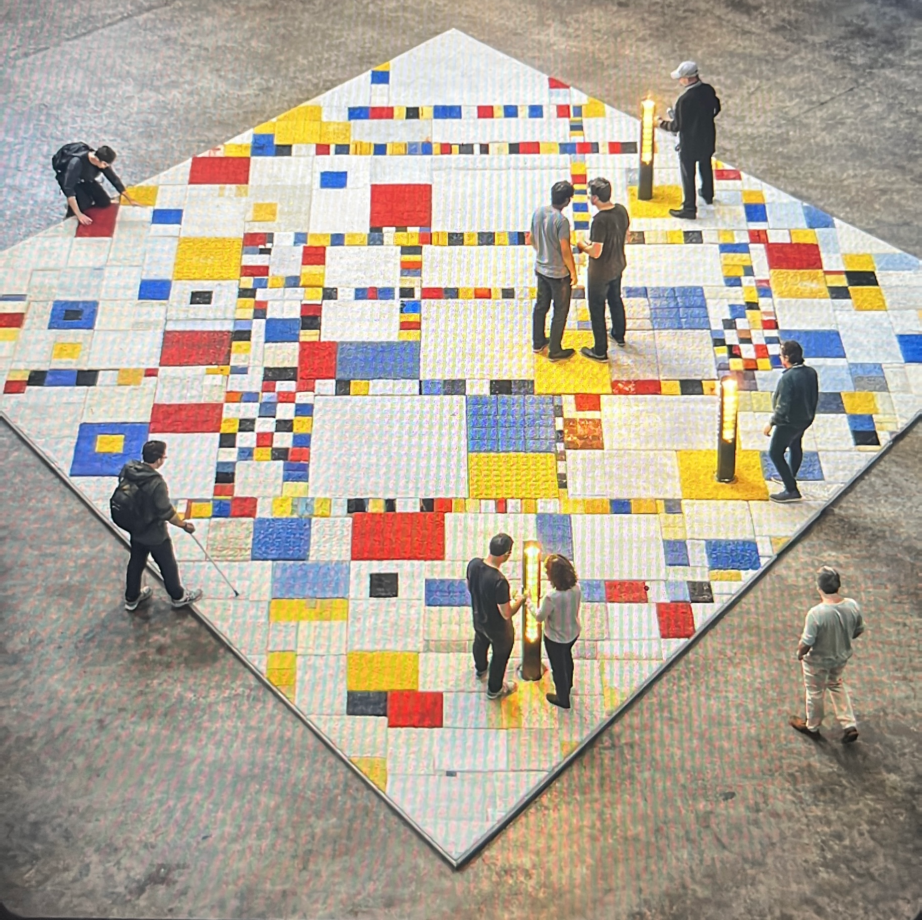 Een ruimtelijke compositie met Mondriaan-achtige kleurvlakken en bezoekers in de ruimte.